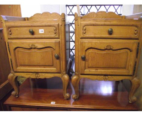 A pair of continental medium to light oak bedside cupboards, each enclosed by a fielded panelled door beneath a frieze drawer