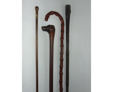 Antique walking canes to include a timber example terminating in a carved dog's mask, a bamboo example with crooked handle, a