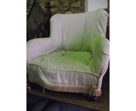 An Edwardian drawing room chair with shaped outline, generous seat, upholstered finish and later loose cover raised on short 