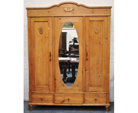 Pine triple wardrobe, shape cornice, open mirror panel, flanked by a panel doors, enclosing a hanging rail, three drawers bel
