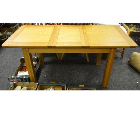 A contemporary light oak draw leaf dining table