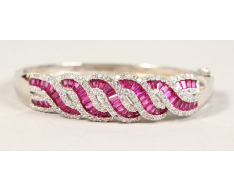 A SILVER, ZIRCON AND RED STONE TWIST BANGLE.