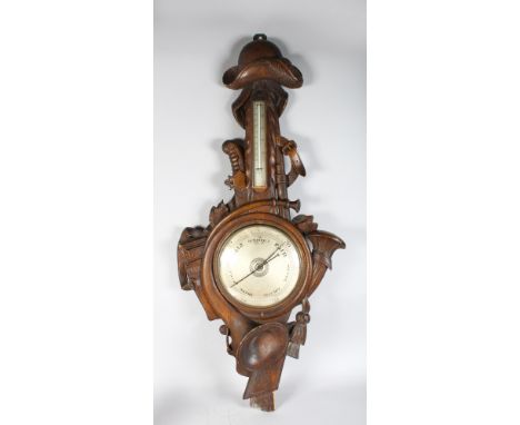 A RARE EARLY 19TH CENTURY BLACK FOREST CARVED WOOD BAROMETER, the case carved with hunting horns, hat, sword, gun etc. 3ft 9i