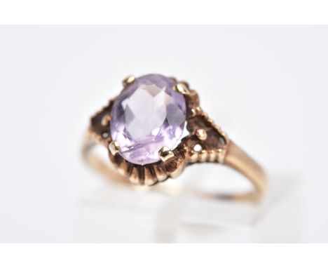 A 9CT GOLD AMETHYST RING, designed with a central claw set, oval cut amethyst within a bead and scallop decorated surround an