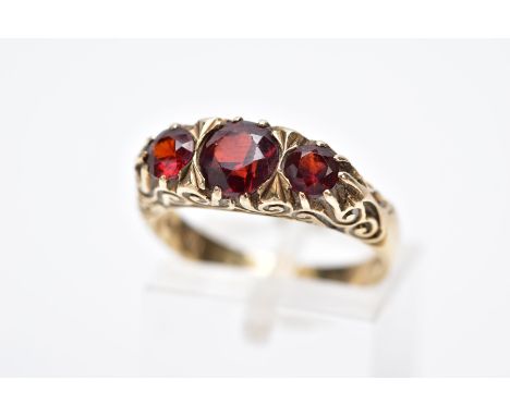 A LATE 20TH CENTURY 9CT GOLD, THREE STONE GARNET RING, designed with three graduated circular cut garnets, scroll detailed ga