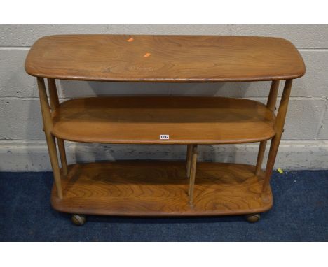 AN ERCOL MODEL 361 BLONDE ELM AND BEECH WINDSOR BOOKCASE TROLLEY, three tiers, the bottom tier with spindles, on orbit caster