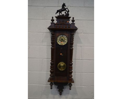 A MAHOGANY VIENNA WALL CLOCK, with a ceramic horse pediment, various turned finals, the door enclosing a 6 inch dial with rom