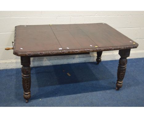 AN EARLY 20TH CENTURY CARVED OAK WIND OUT DINING TABLE, with one additional leaf on turned legs with ceramic casters, extende