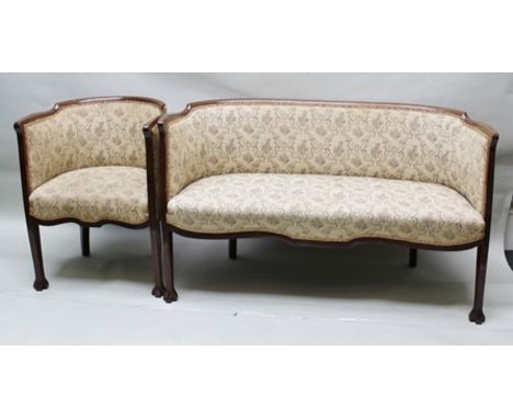 AN EDWARDIAN MAHOGANY SHOW WOOD FRAMED TWO SEATER SETTEE raised on cross frame feet, together with the matching TUB CHAIR uph