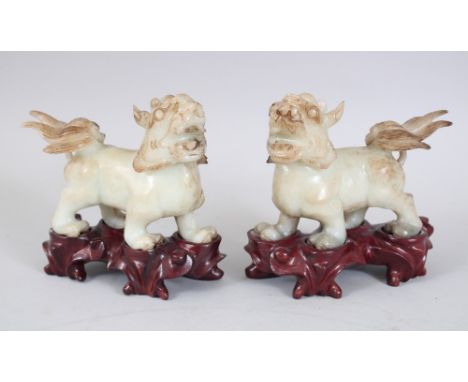 A PAIR OF 20TH CENTURY CHINESE JADE / SOAPSTONE LION DOGS ON STANDS, the pair of fo dogs on fitted hardwood stands, overall 1