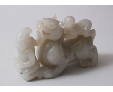 A GOOD CHINESE CARVED JADE / HARDSTONE PEN OR BRUSH HOLDER, carved in the form of a lion dog with two figures, 7cm high x 12c