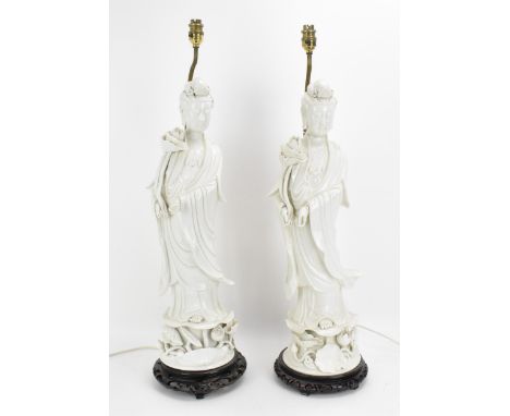 Two large Chinese Dehua figures of Guanyin, Republic period, with draped clothing, holding a lotus flower, standing on a lotu