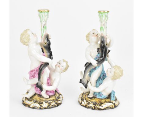 Two Meissen figural candlesticks, 19th century, each modelled as two putti supporting a fish issuing a candle sconce, on a na