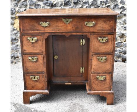 An early George III walnut and feather-banded kneehole desk, the bookmatched veneer top with herringbone string inlay border,