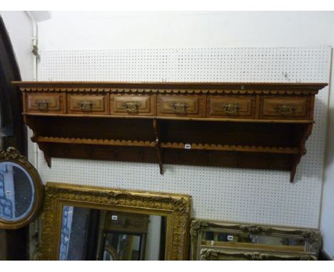 A Pitch pine hall/kitchen wall shelf, fitted with six frieze drawers, shaped brackets and run of brass hooks, 165 cm wide app