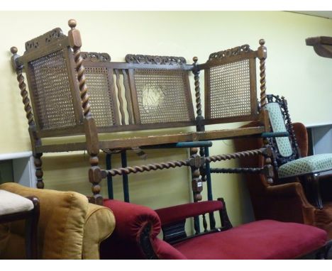 An Edwardian sofa in the Carolean style with barley twist supports, pierced cresting rails and cane panelled back and sides