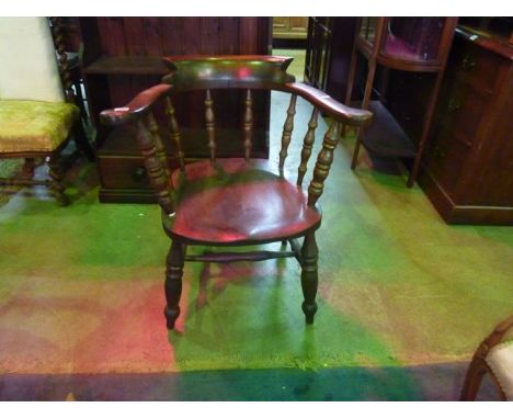 A 19th century smokers bow elbow chair with turned spindle back over a solid saddle shaped seat raised on turned supports uni