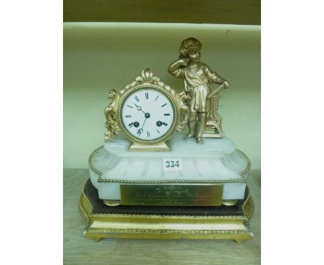 A Victorian alabaster and spelter mantel clock enclosing an 8-day striking movement surmounted by a young scholar, set on a g
