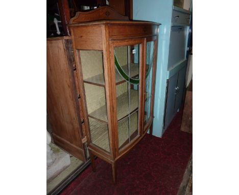 An Edwardian oak freestanding bow fronted display cabinet with ebonised string inlaid and further detail and enclosed by a pa