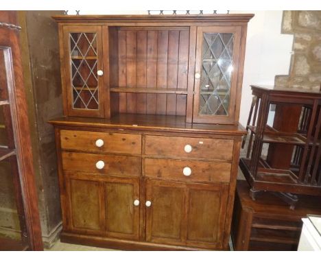 A reclaimed stained pine kitchen dresser, the base partially enclosed by a pair of twin panelled doors beneath an arrangement