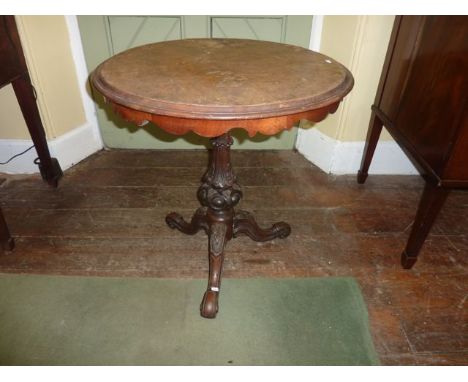 A mid-Victorian walnut occasional table, the circular top with scalloped frieze, raised on a turned and carved vase shaped pi