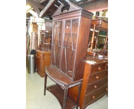 An Edwardian Chippendale revival bookcase with blind fret and pierced detail, broken arch architectural cornice over a pair o