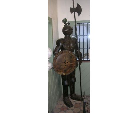 A freestanding reproduction suit of armour, the knight clutching a circular shield with fleur-de-ly detail and long handled a