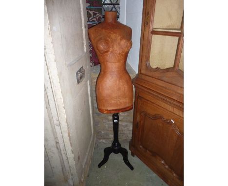 A mannekin of a female torso raised on an ebonised turned tapered column and shaped tripod