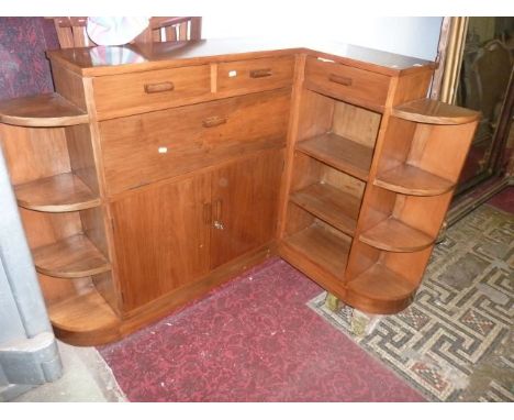 An Art Deco style low freestanding walnut veneered corner bookcase/cupboard fitted with three frieze drawers over a full fron