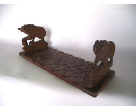 A late 19th/early 20th century Black Forest type sliding timber book shelf with hinged capitals in the form of bears standing