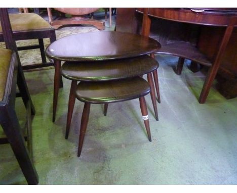 A nest of three graduated Ercol dark stained elm and beechwood "pebble" occasional tables with simple stick supports