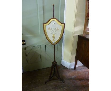 A 19th century mahogany pole screen in the Adams style, the tripod base with reeded detail, supporting a shield shaped frame,