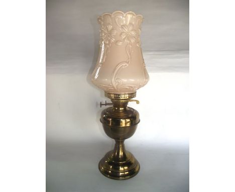A brass oil lamp with Duplex burner and pale pink opaque pressed shade with moulded floral decoration and clear glass chimney