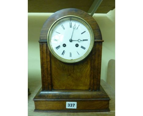 A figured walnut mantel clock with domed case enclosing an enamel dial with 8-day striking movement