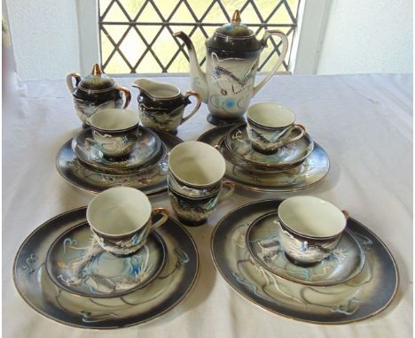 A collection of Japanese eggshell porcelain coffee wares with moulded and painted dragon decoration on a graduated black and 