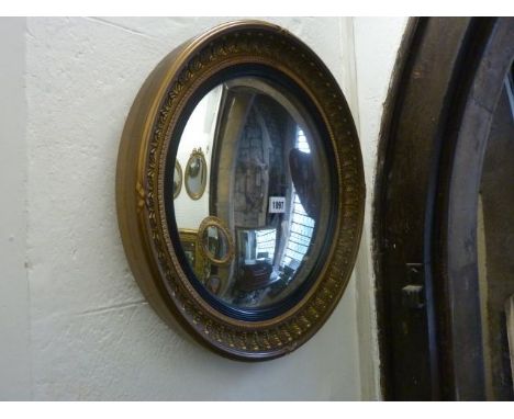 A reproduction Regency style convex wall mirror with ebonised reeded slip and foliate surround