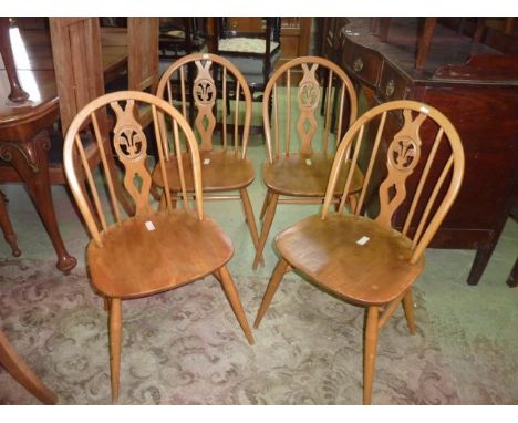 A set of four Ercol elm and beechwood hoop and stick back dining chairs with central pierced splats with fleur-de-lys detail 