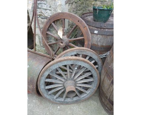 A pair of vintage wooden cartwheels with iron rims and timber spokes together with one other