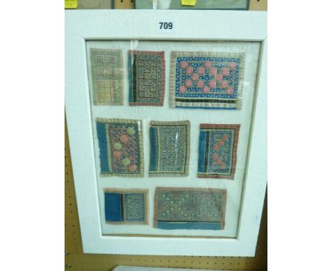 A montage of eight eastern embroidered and appliqued panels predominantly in tones of red, blue and cream, in single white pa