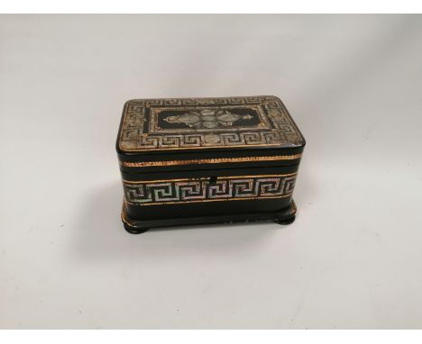A 19th Century black lacquered tea caddy raised on four bun feet,  with inset mother of pearl floral motif and Greek key desi