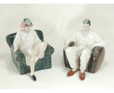 A pair of mid to late 20th Century moulded ceramic figures seated in armchairs,  staring directly ahead as if watching televi