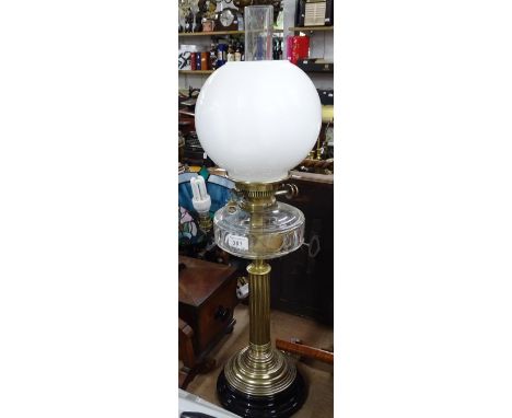A fluted brass oil lamp with glass font and shade.