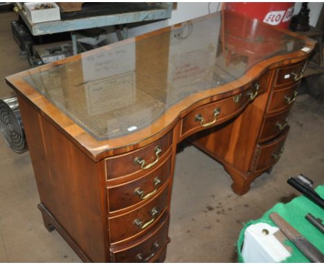 A reproduction yewwood serpentine writing desk with inset leather skiver, 9 fitted drawers, bracket feet, width 115cm, height
