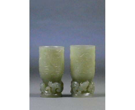 A pair of Chinese celadon jade vases, the cylindrical bodies decorated with dragons and scrolls with similar raised decoratio