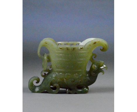 A Chinese carved jade libation cup with flared spout, archaic incised decoration to the boy and raised on a stylised phoenix 