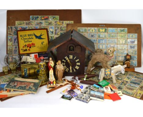 A collectors lot comprising a cuckoo clock (af), cigarette cards depicting animals mounted on boards, a tin containing collec