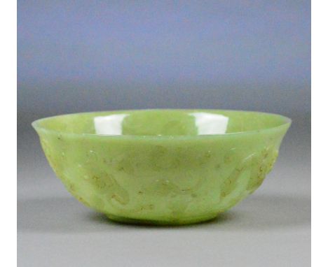A Chinese pale jade bowl decorated with stylised dragons amongst scrolls, diameter 16.5cm.