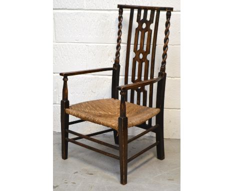 An early 20th century oak low chair on bobbin turned supports and rush seat.