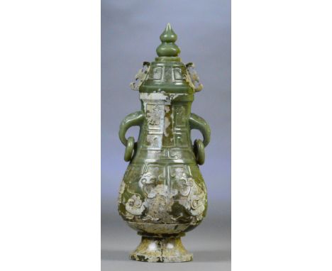 A Chinese jade and russet included twin handled vase and cover with drop ring handles and stylised raised decoration etched g