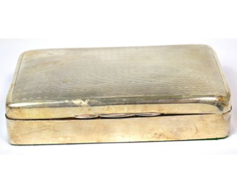 A George V hallmarked silver engine turned cigarette box with engraving 'A.J.A.', Chester 1911, length 16cm, containing packe